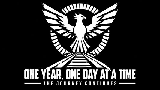 Black-and-white cyberpunk phoenix rising above a path with the words “ONE YEAR, ONE DAY AT A TIME” and “THE JOURNEY CONTINUES